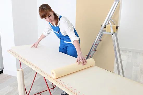 Person rollt Tapete auf Tisch aus